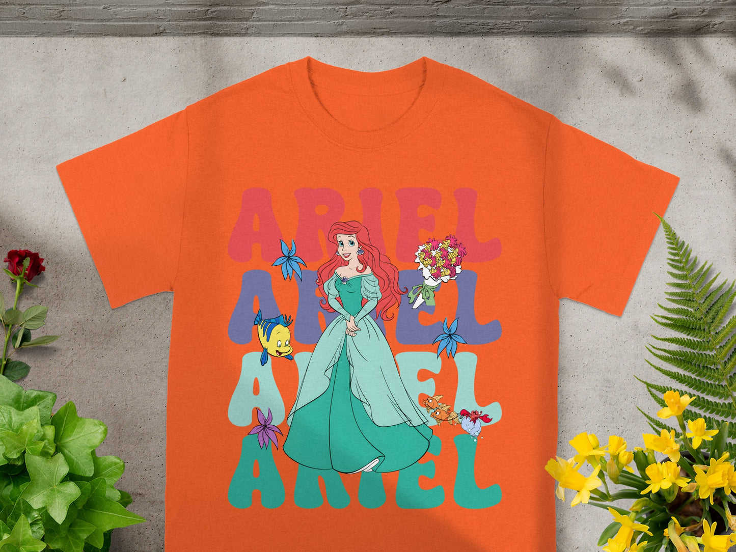 Ariel from The Little Mermaid on an orange t-shirt with large text.