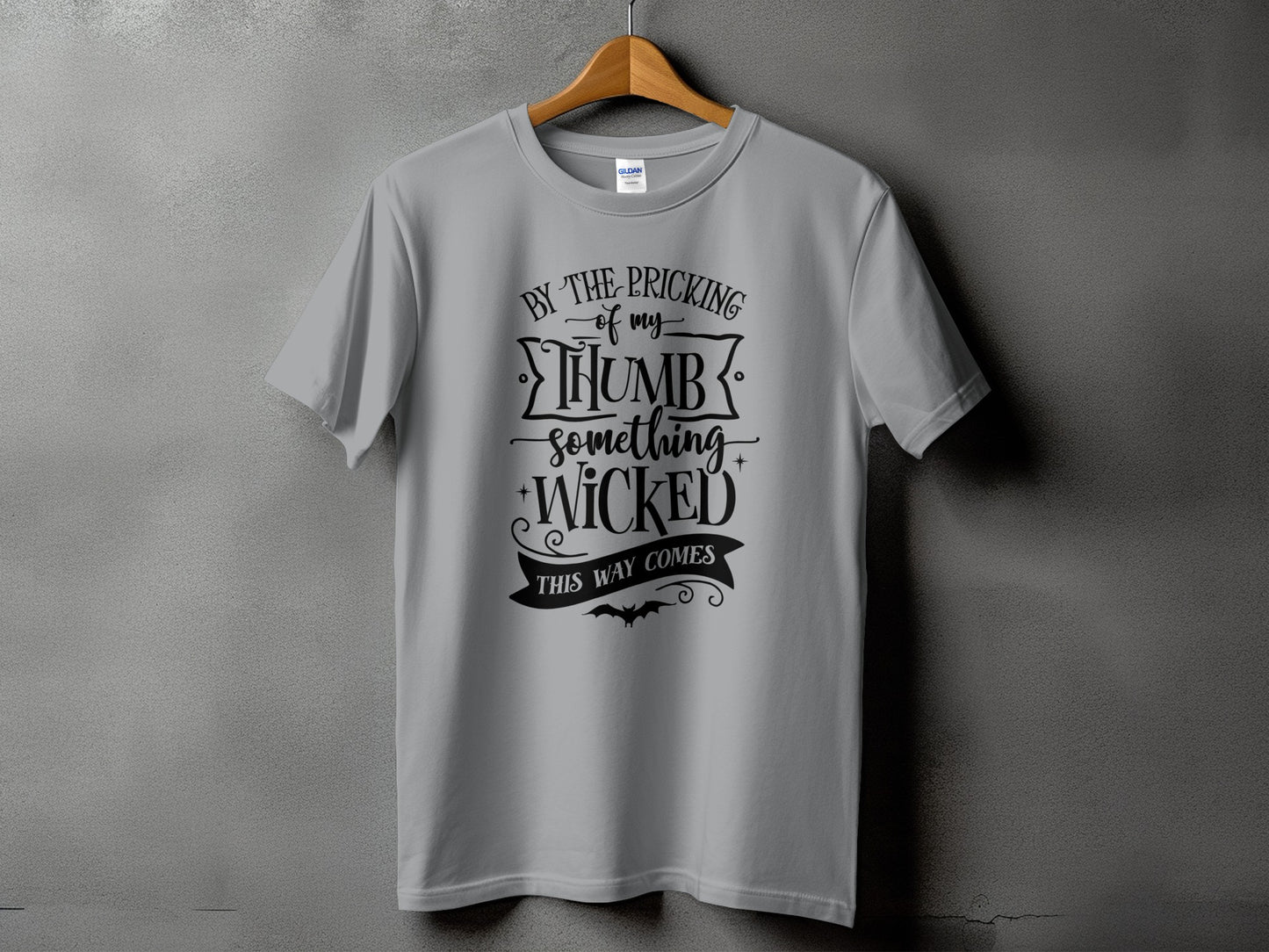 Grey t-shirt with black text "By the pricking of my thumb something wicked this way comes."