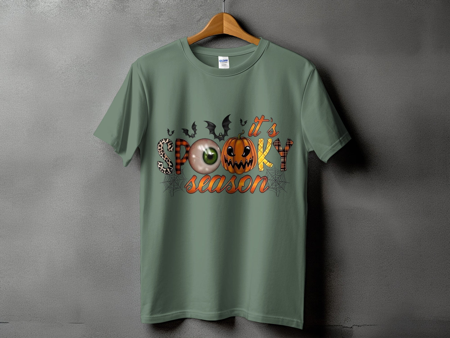 Green t-shirt with "it's SPOOKY season" Halloween graphic featuring bats, eyeball, and pumpkin.