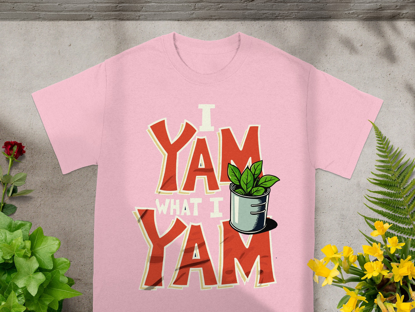 Pink t-shirt with "I Yam What I Yam" text and a potted plant.