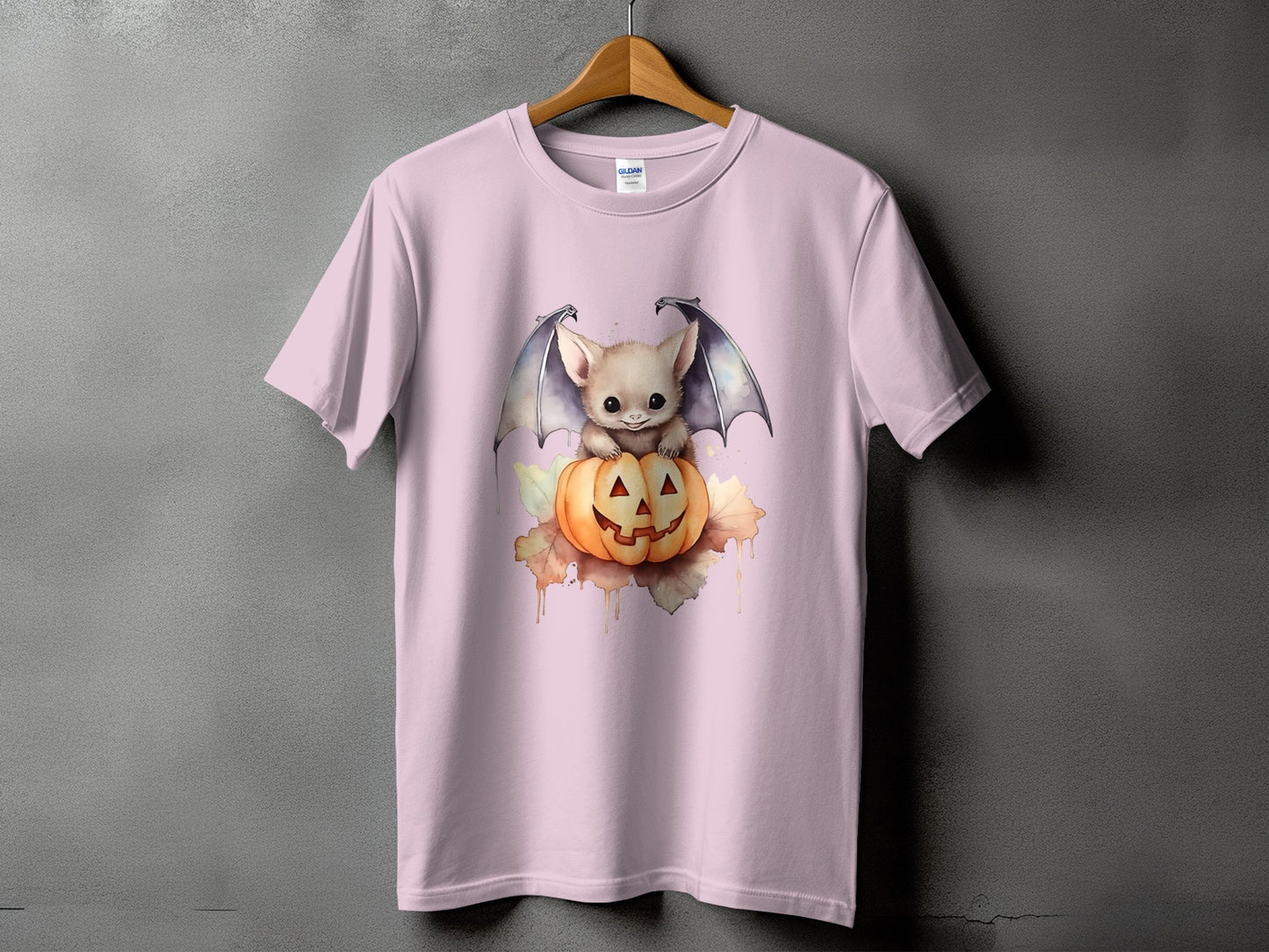 Pink t-shirt with a cute bat sitting on a jack-o'-lantern with fall leaves.