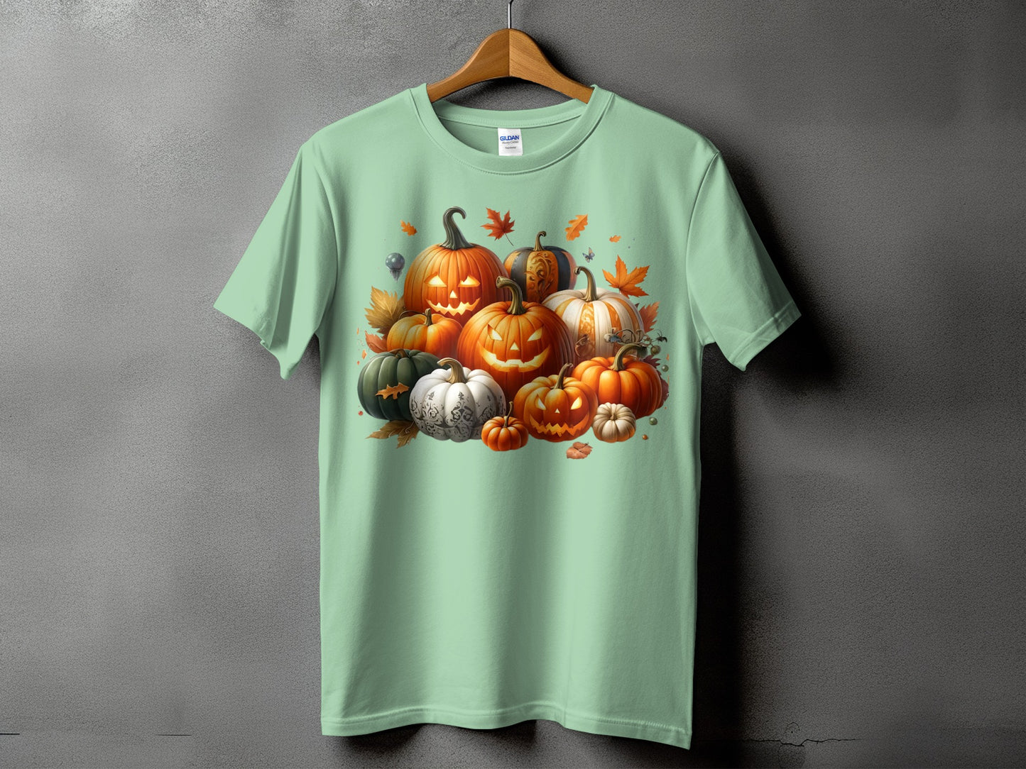 Mint green t-shirt with a cluster of carved and decorative pumpkins and autumn leaves.