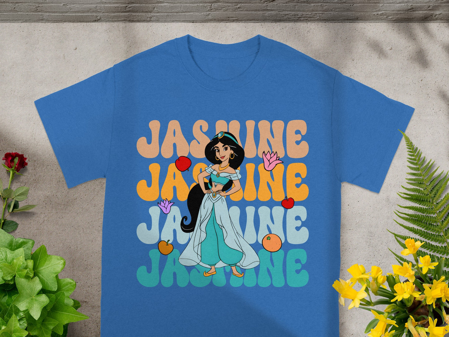 Blue t-shirt with "Jasmine" in colorful, retro lettering and character illustration.