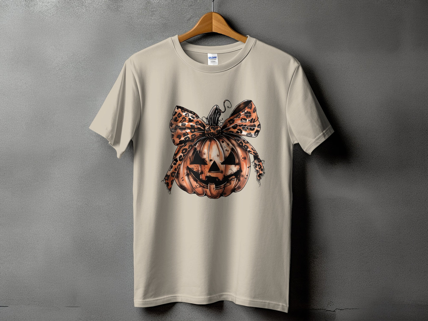 Light tan t-shirt featuring a Halloween jack-o'-lantern with a leopard print bow.