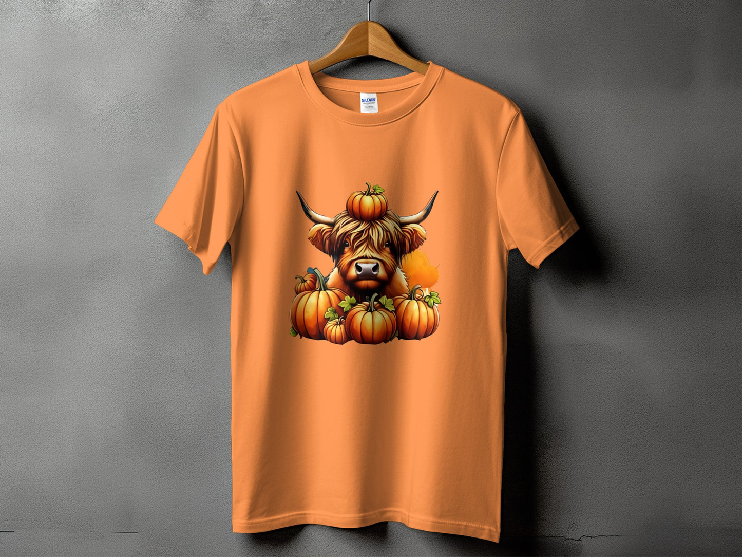 Orange t-shirt featuring a Highland cow with pumpkins and a pumpkin on its head.