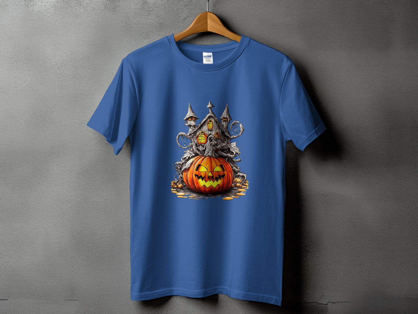 Blue t-shirt featuring a Halloween graphic of a haunted house atop a jack-o'-lantern.