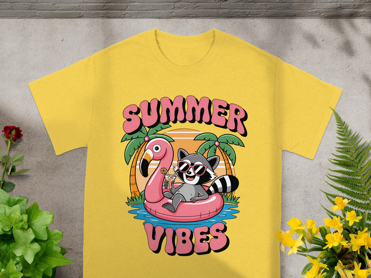 Yellow t-shirt with cartoon raccoon on flamingo float, "SUMMER VIBES" text.