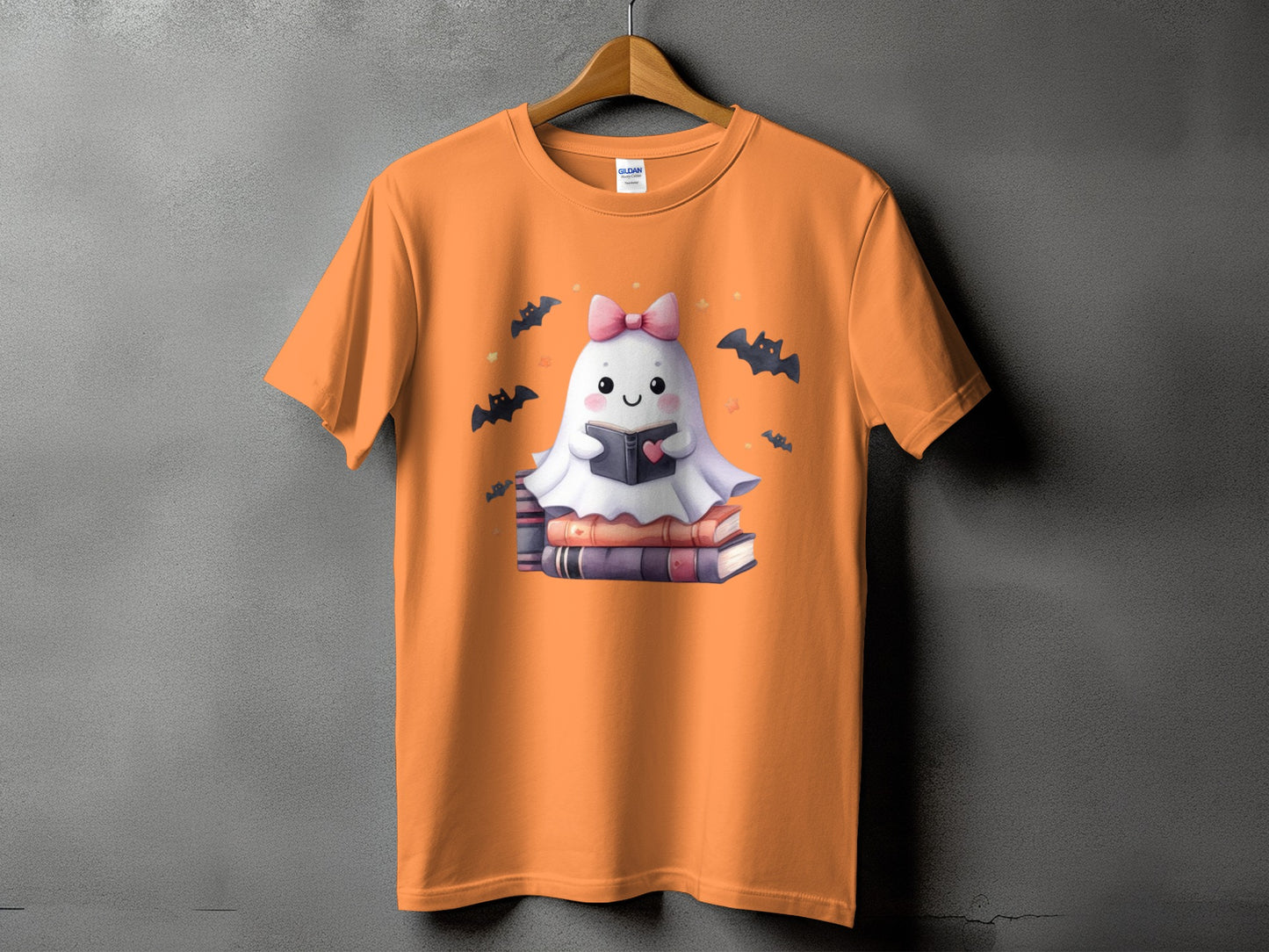 Orange t-shirt with a cute ghost reading a book surrounded by bats.