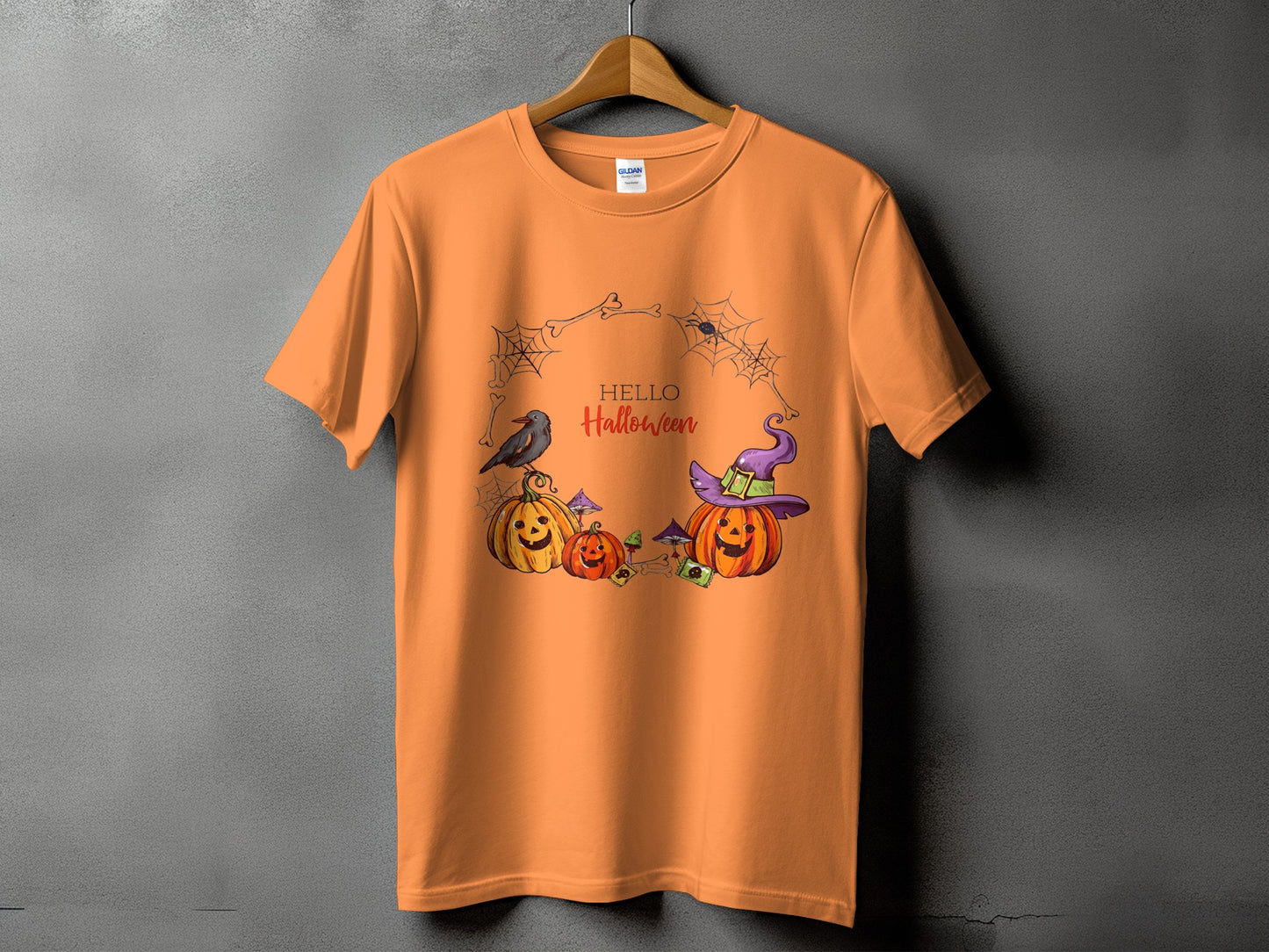 Orange t-shirt with "Hello Halloween" text and cartoon pumpkins, crow, witch hat, and spiders.