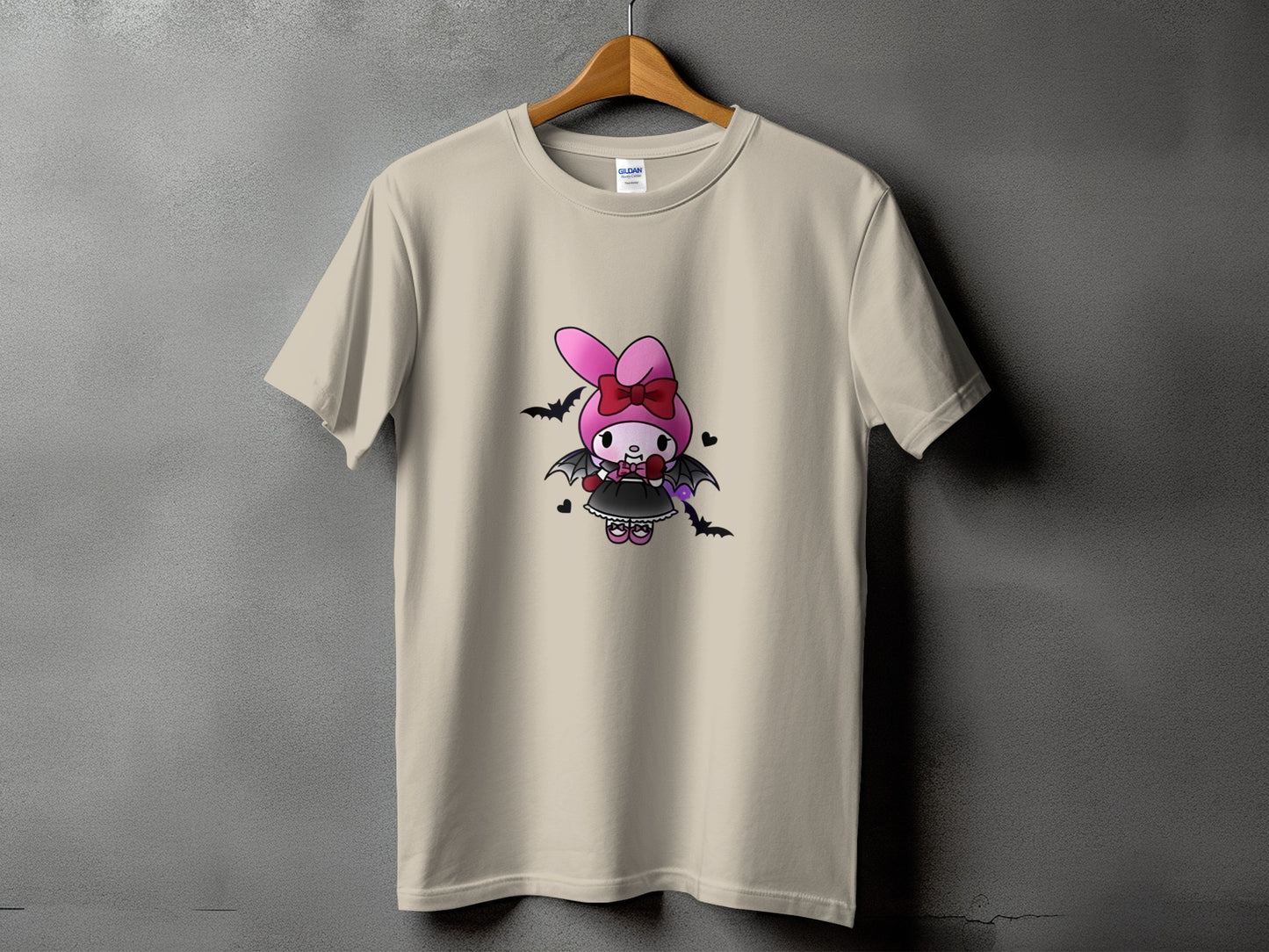 Beige t-shirt with a cartoon bunny wearing a pink bow and bat wings.