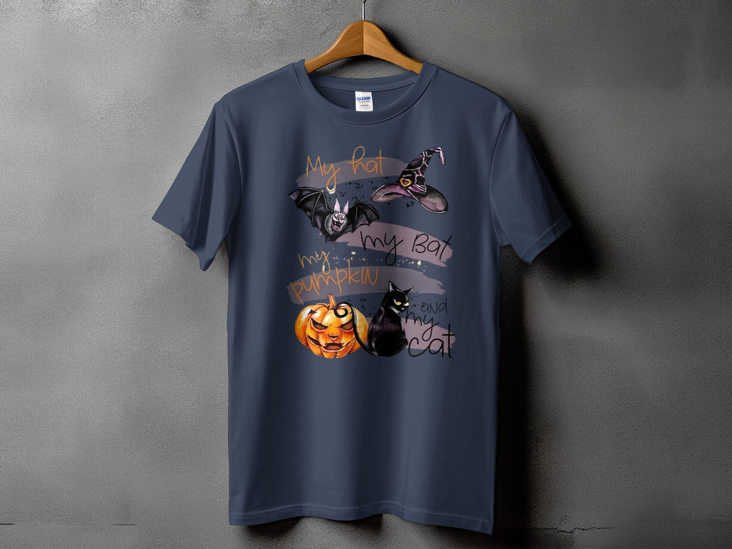 Dark t-shirt with Halloween graphic featuring a bat, witch hat, pumpkin, and cat.