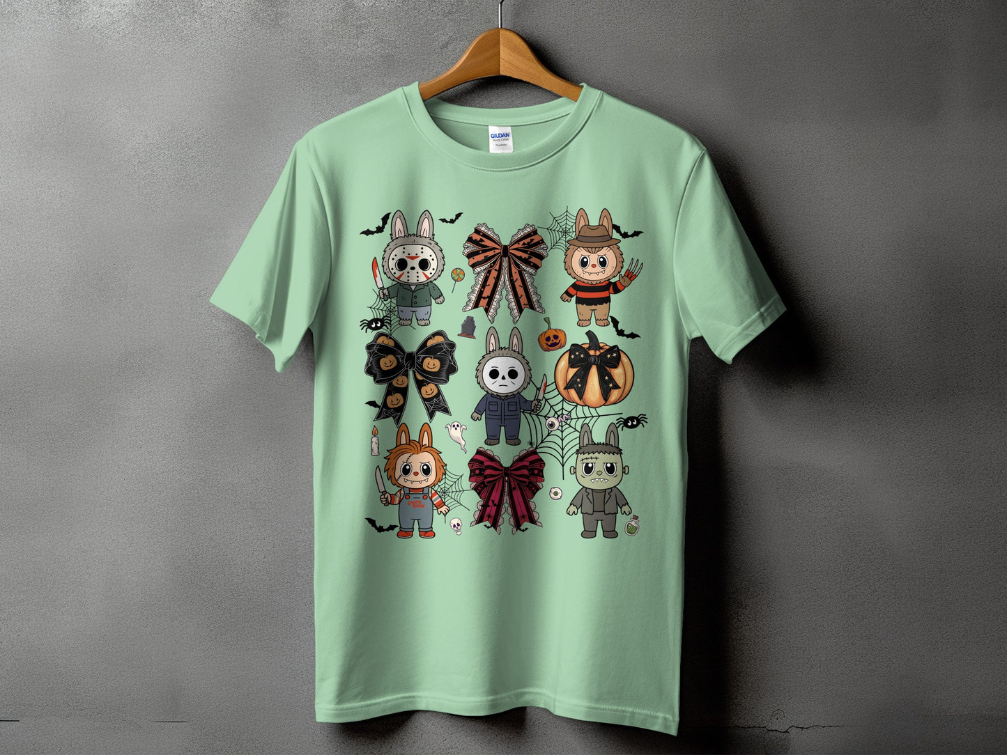 Mint green t-shirt with assorted cartoon Halloween characters and bows graphic print.