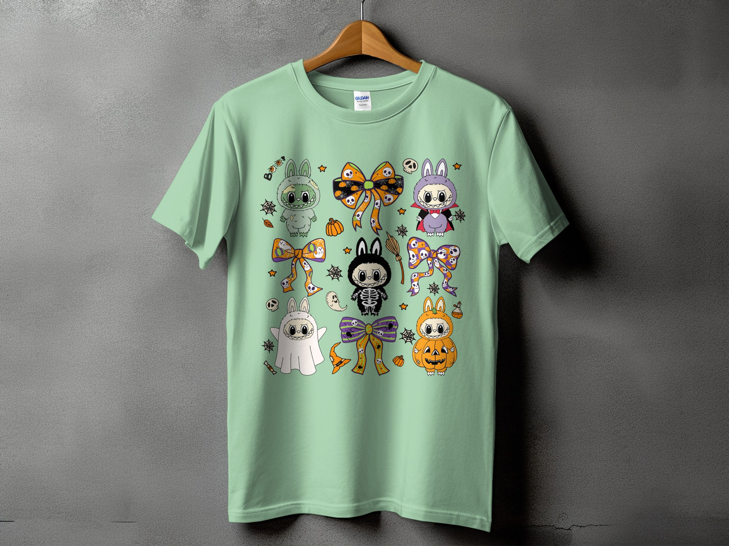 Mint t-shirt with a repeating pattern of cute Halloween characters and bows.