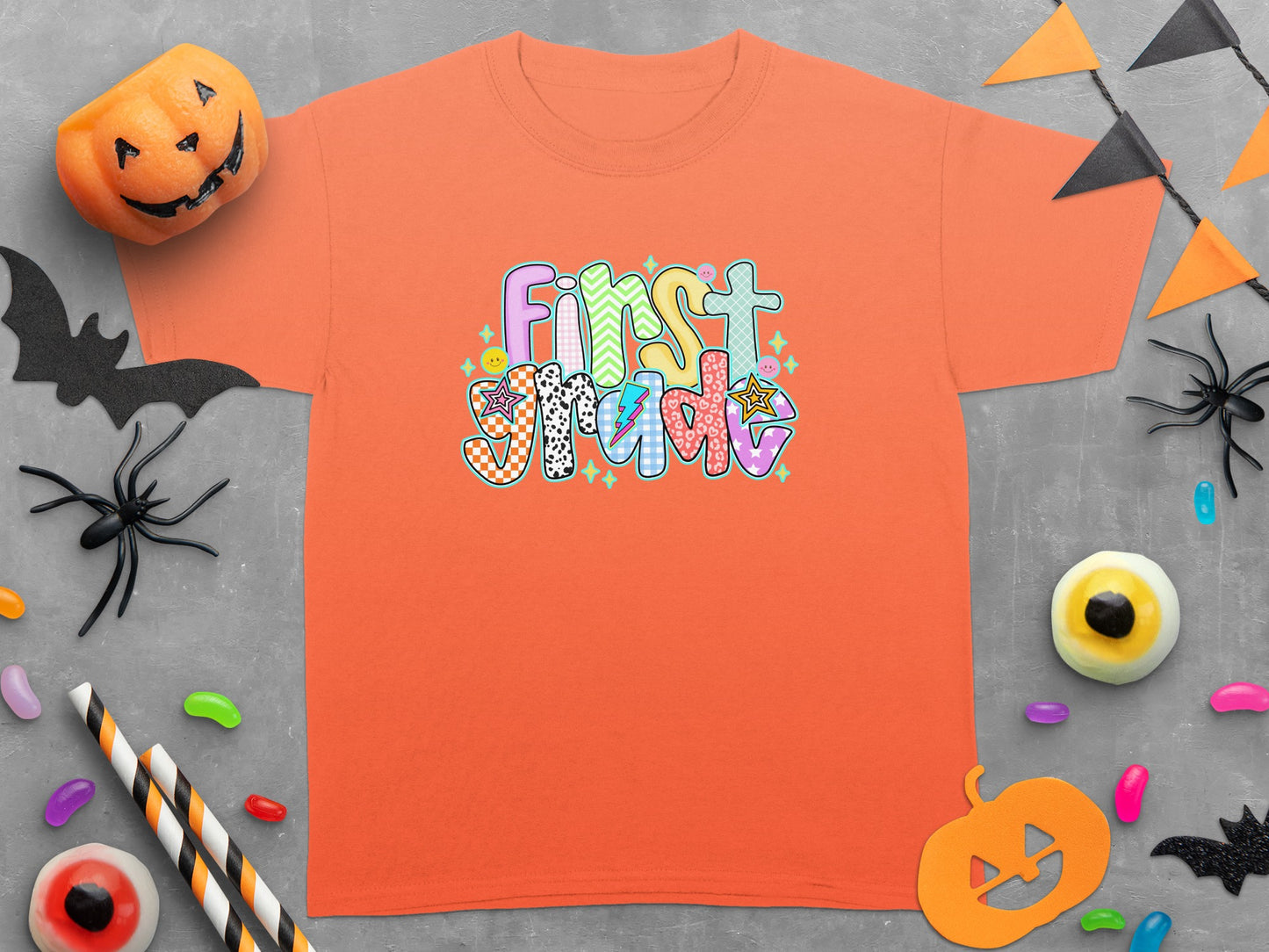 Orange t-shirt with "First Grade" in colorful, patterned letters.