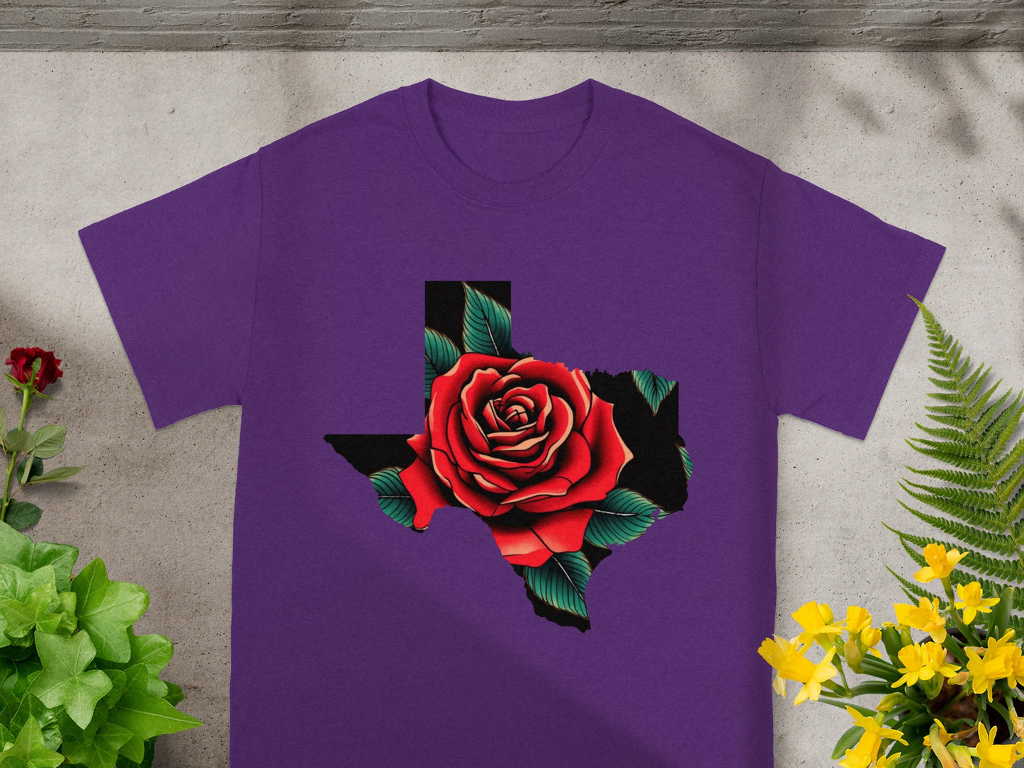 Purple t-shirt with a Texas outline filled by a red rose design.