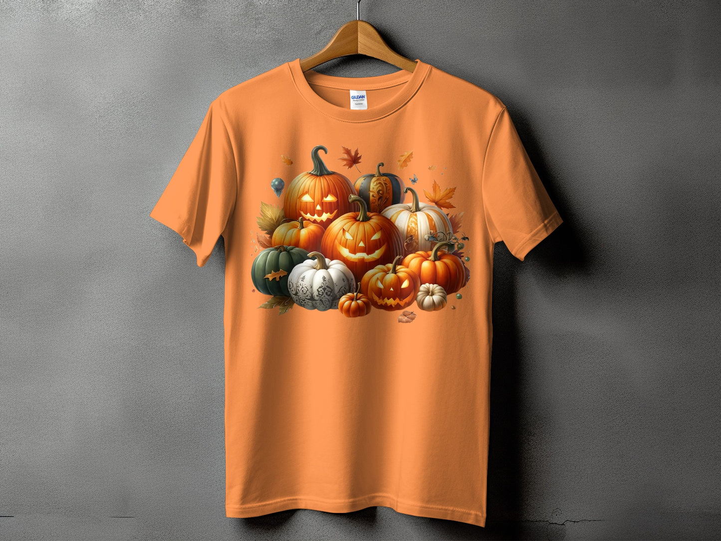 Orange t-shirt featuring a pile of carved and decorative pumpkins and autumn leaves.