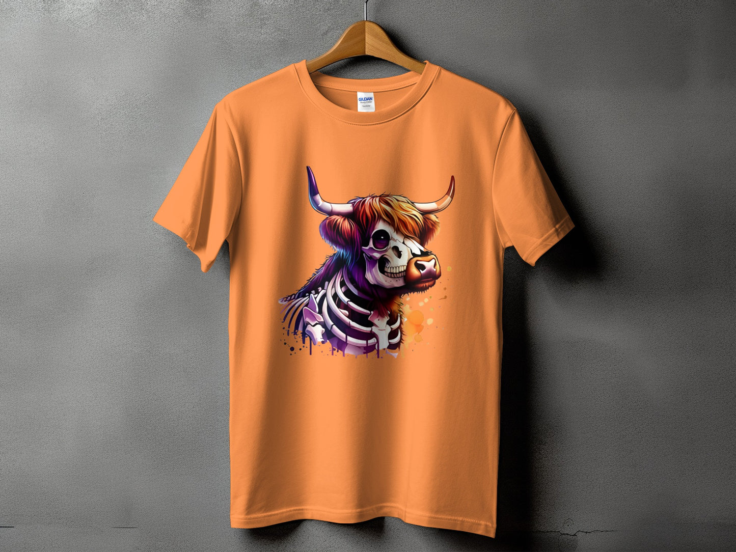 Orange t-shirt with a skeletal Highland cow graphic featuring colorful splashes.