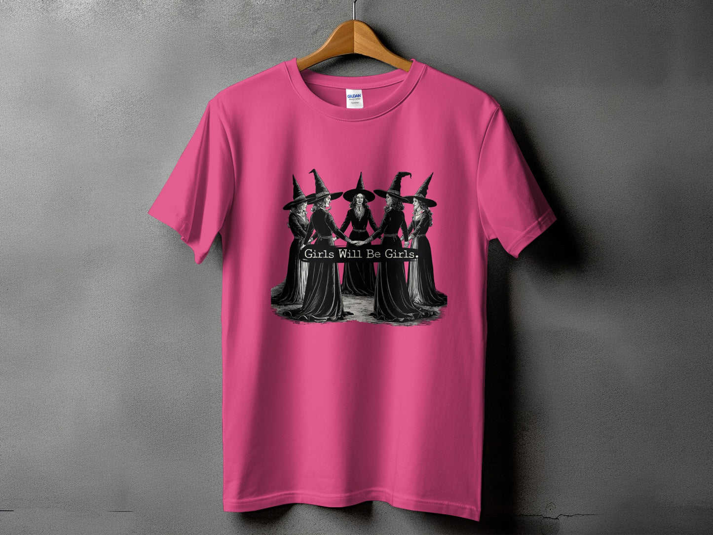 Pink t-shirt with graphic of five witches holding hands and text "Girls Will Be Girls."