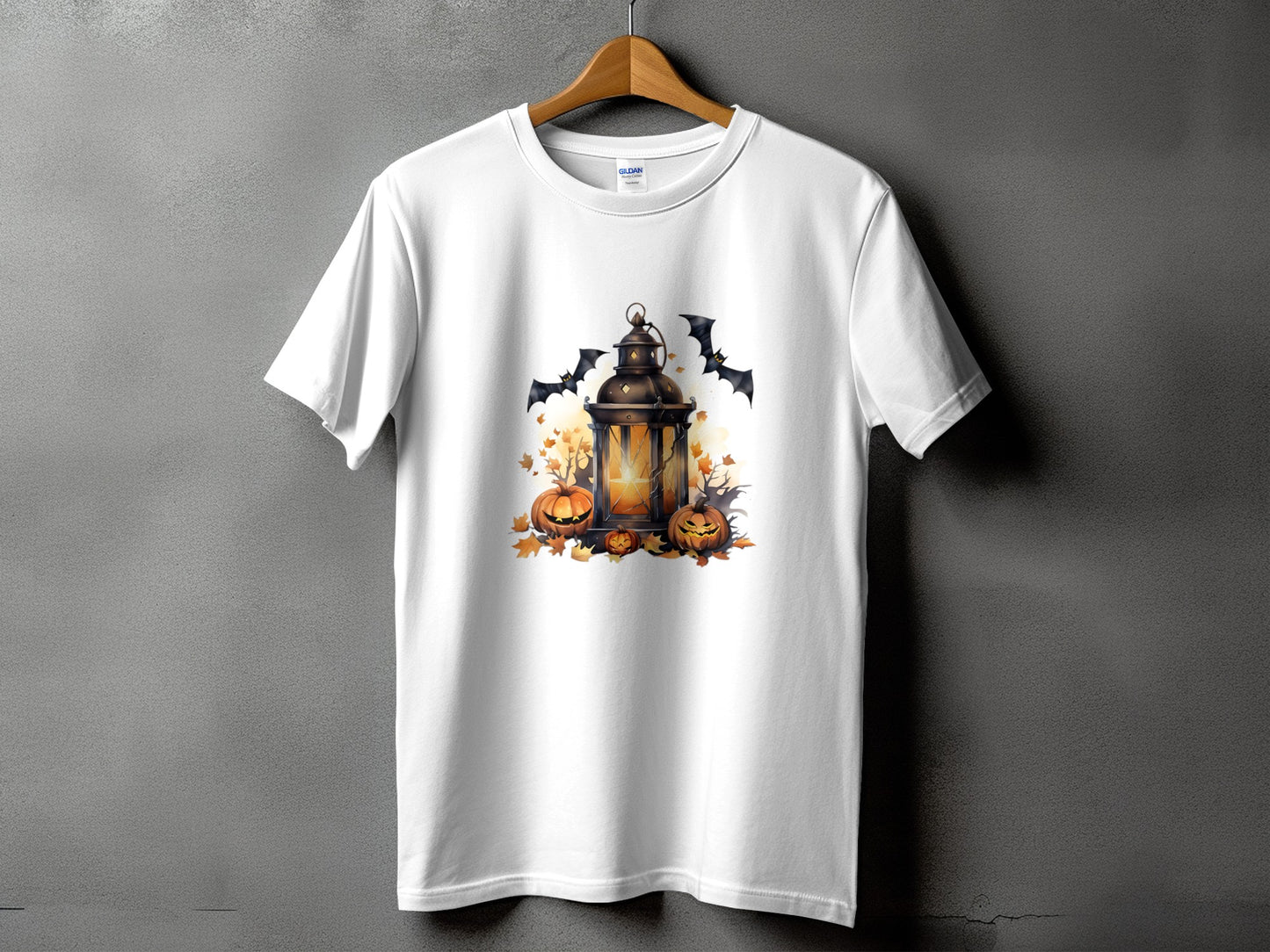 White t-shirt with Halloween graphic of lantern, pumpkins, bats, and autumn leaves.