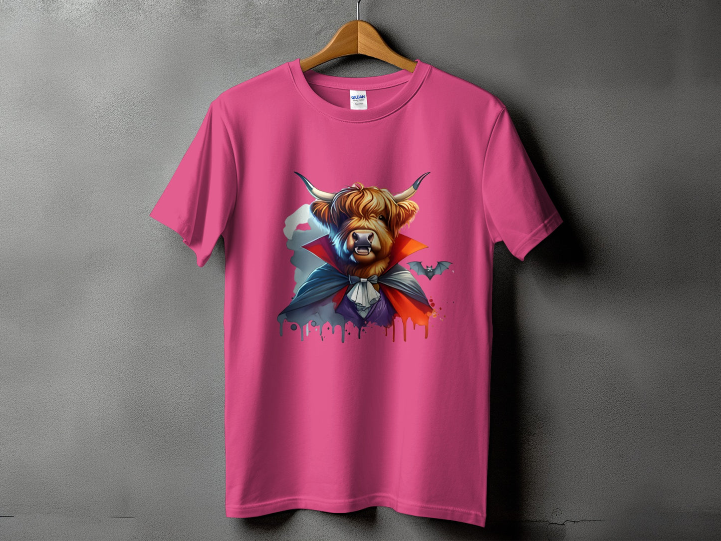 Highland cow dressed as a vampire with a bat on a pink t-shirt.