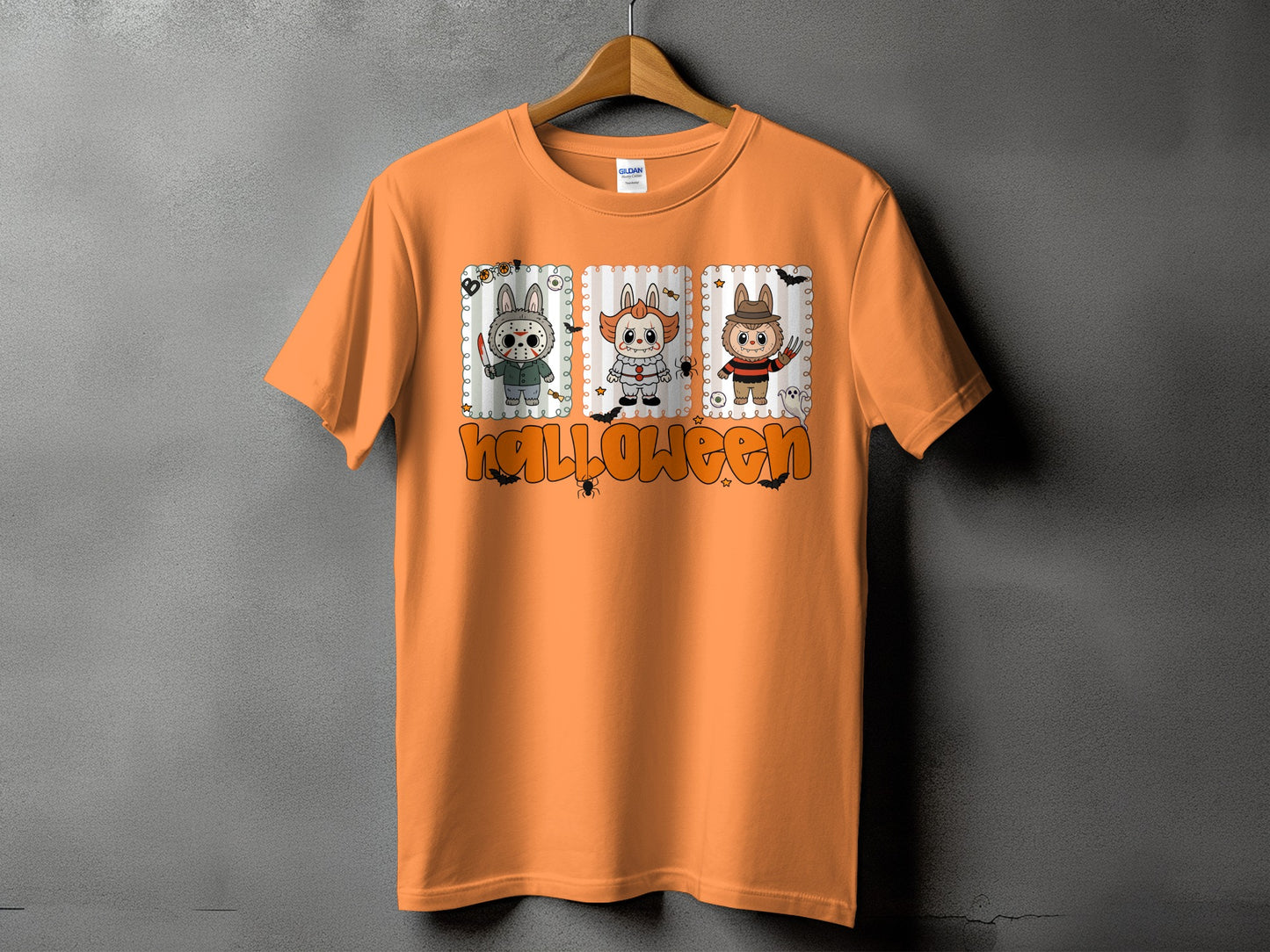 Orange t-shirt with Halloween design featuring three cartoon monsters and text.