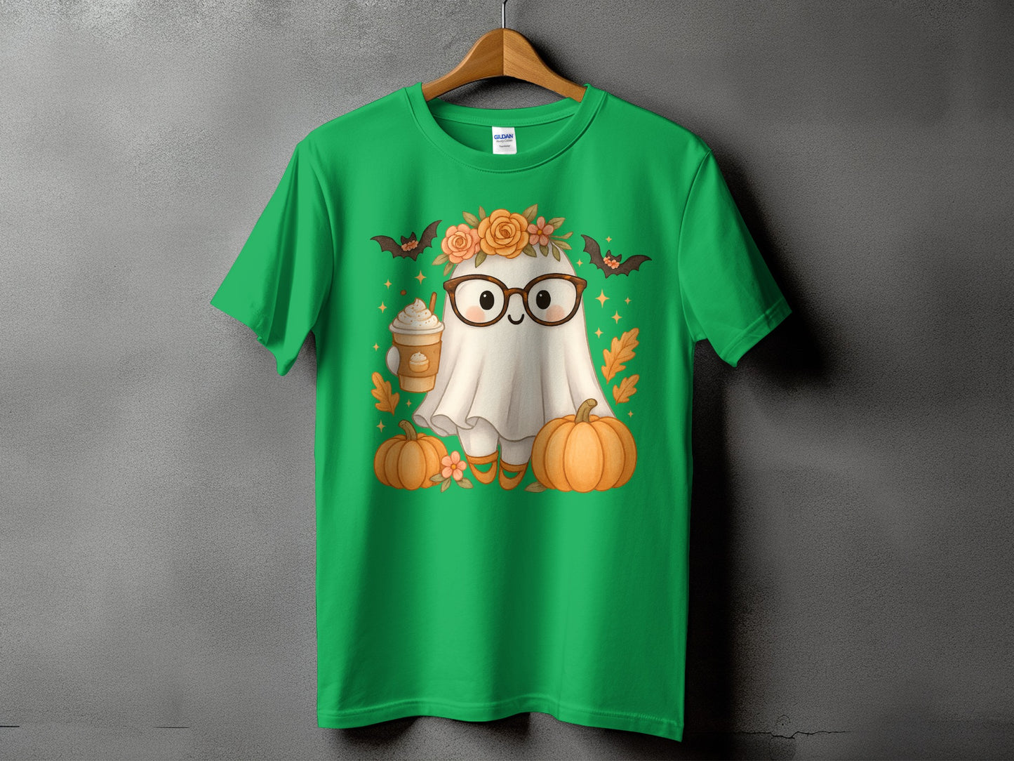 Green t-shirt with a cartoon ghost wearing glasses and a flower crown, holding coffee, with pumpkins.