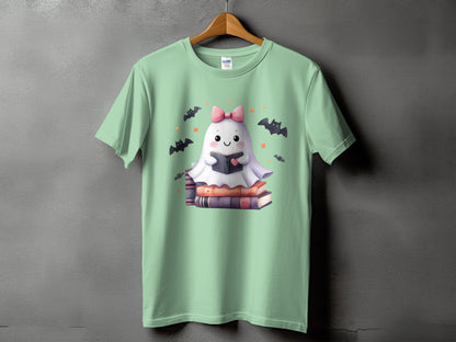 Cute ghost reading a book, surrounded by bats and stars, on a light green t-shirt.