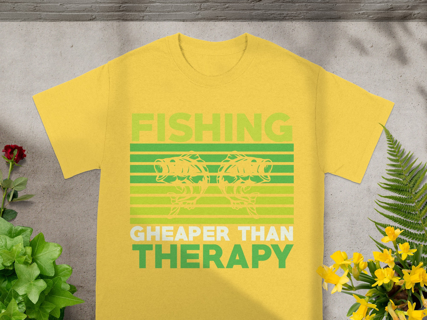 Yellow t-shirt with text "FISHING CHEAPER THAN THERAPY" and two fish graphics.
