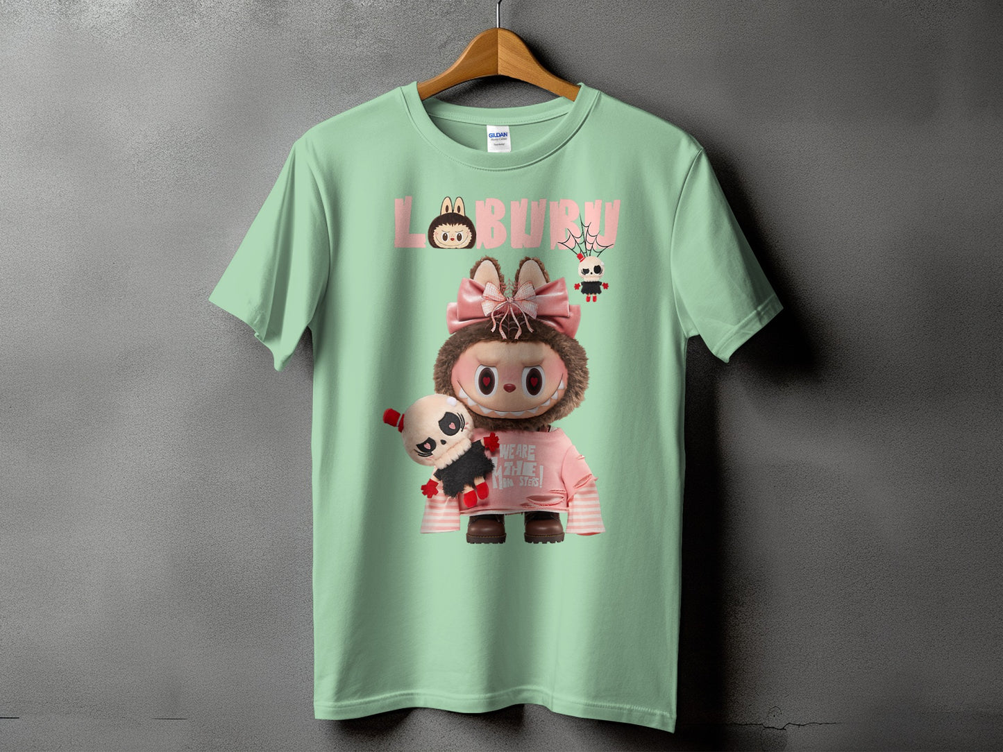 Mint green t-shirt with "LABURU" and monster graphic with small plush toy.