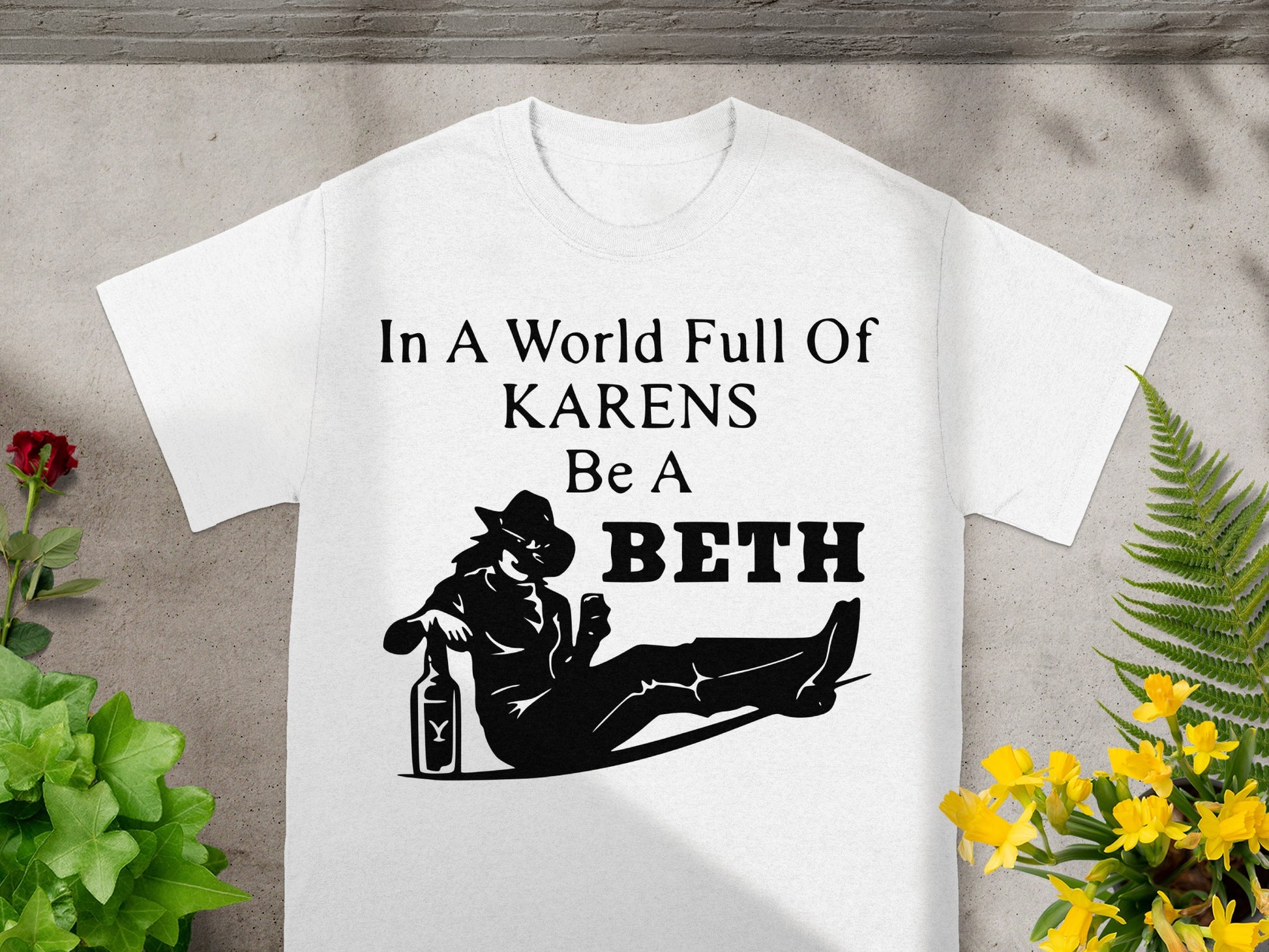White t-shirt with black text and graphic: "In A World Full Of KARENS Be A BETH"
