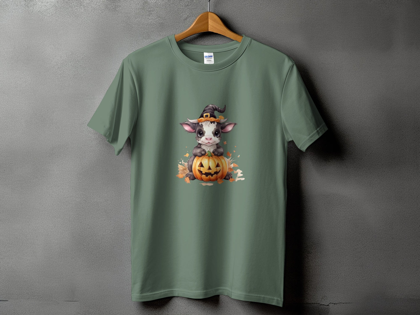 T-shirt with a cartoon cow wearing a witch hat on a pumpkin.