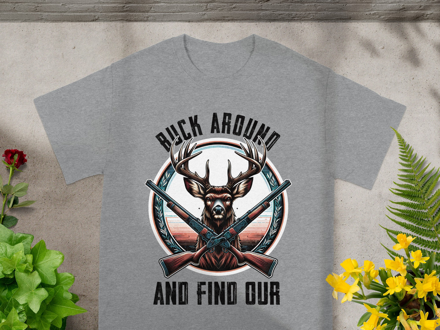 Grey t-shirt with a buck and crossed rifles graphic, text reads "Buck Around And Find Our".