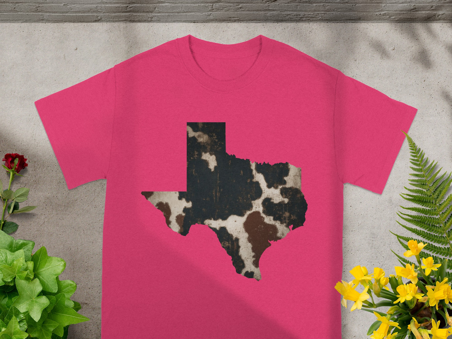 Pink t-shirt with a distressed cowhide print Texas shape graphic.