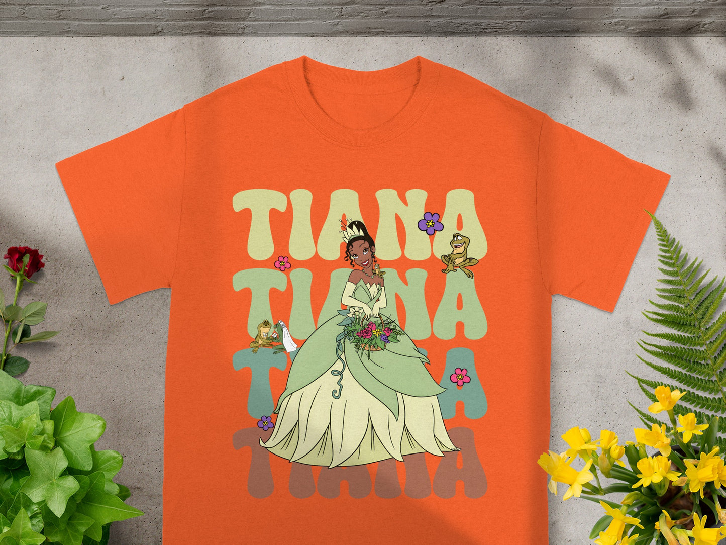 Orange t-shirt with Tiana graphic and floral accents.