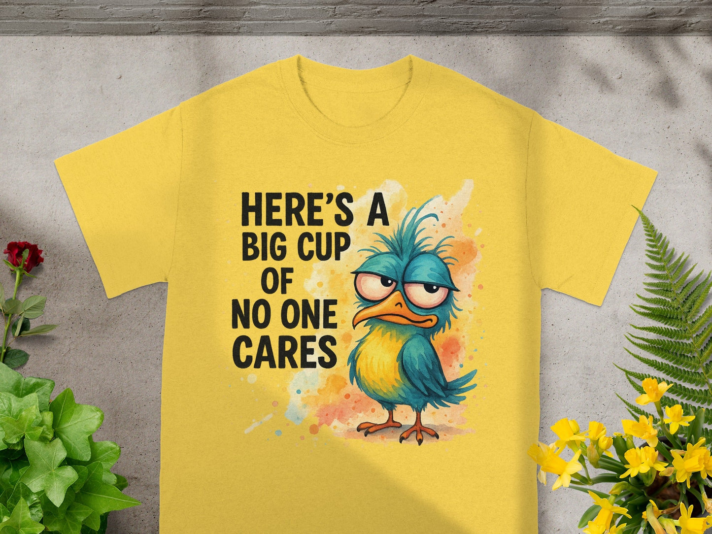 Yellow t-shirt with cartoon bird and text "HERE'S A BIG CUP OF NO ONE CARES".