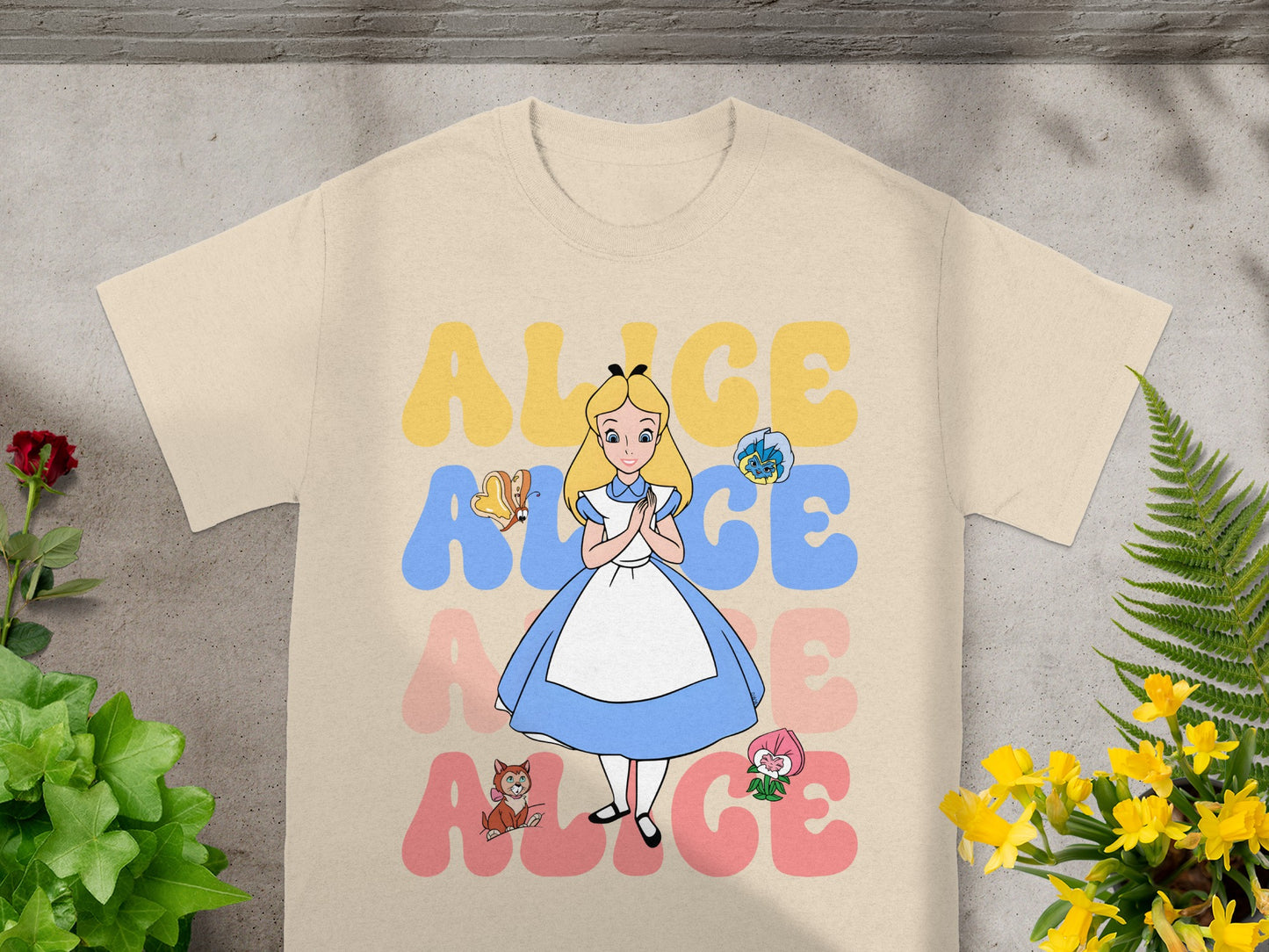 Alice in Wonderland illustration with text, on a tan t-shirt.