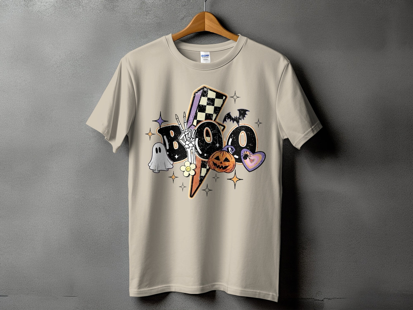 Tan t-shirt with colorful "BOO" Halloween graphic featuring ghosts, pumpkin, and bats.