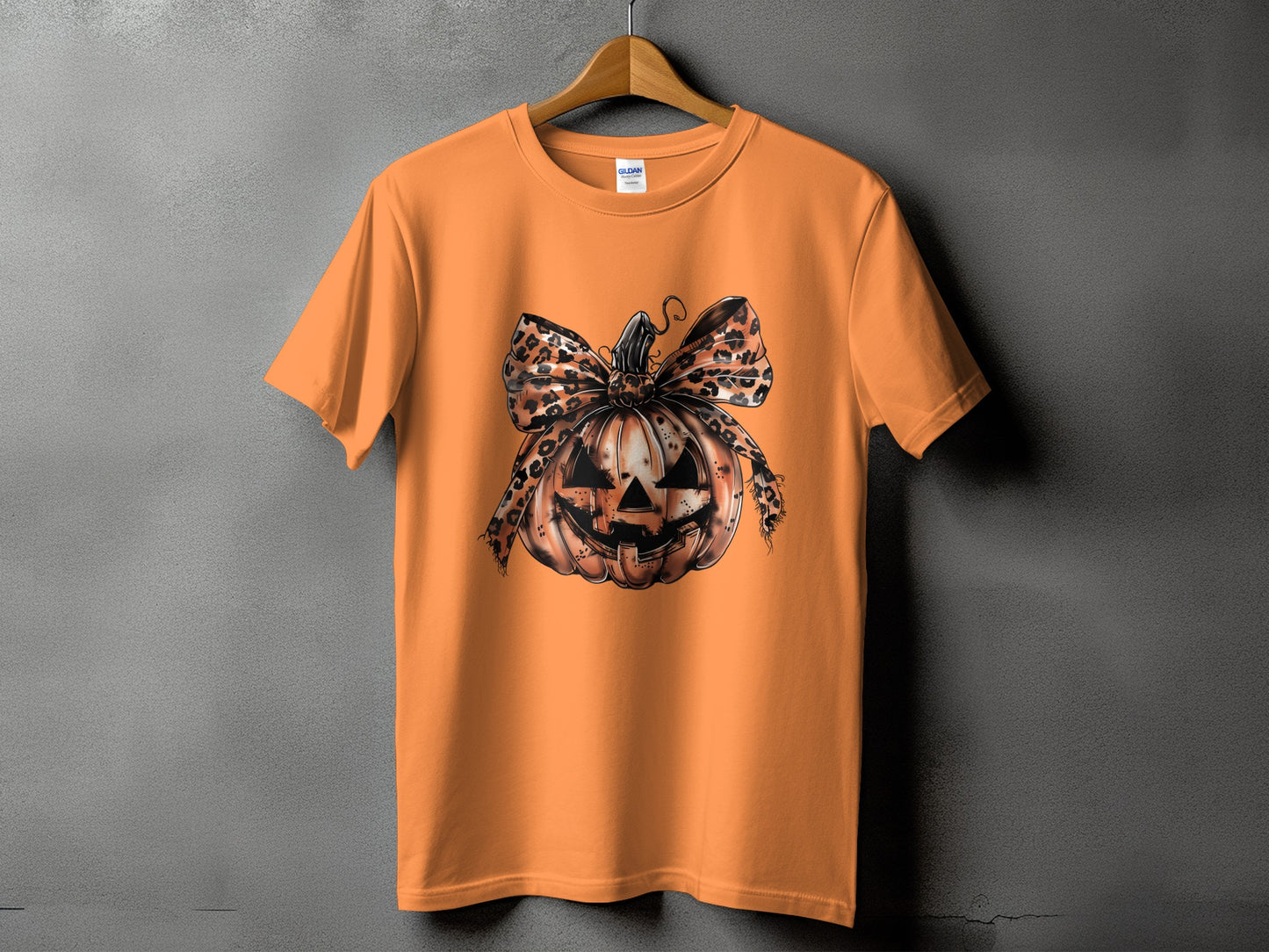 Orange t-shirt with a Halloween pumpkin graphic featuring a leopard print bow.