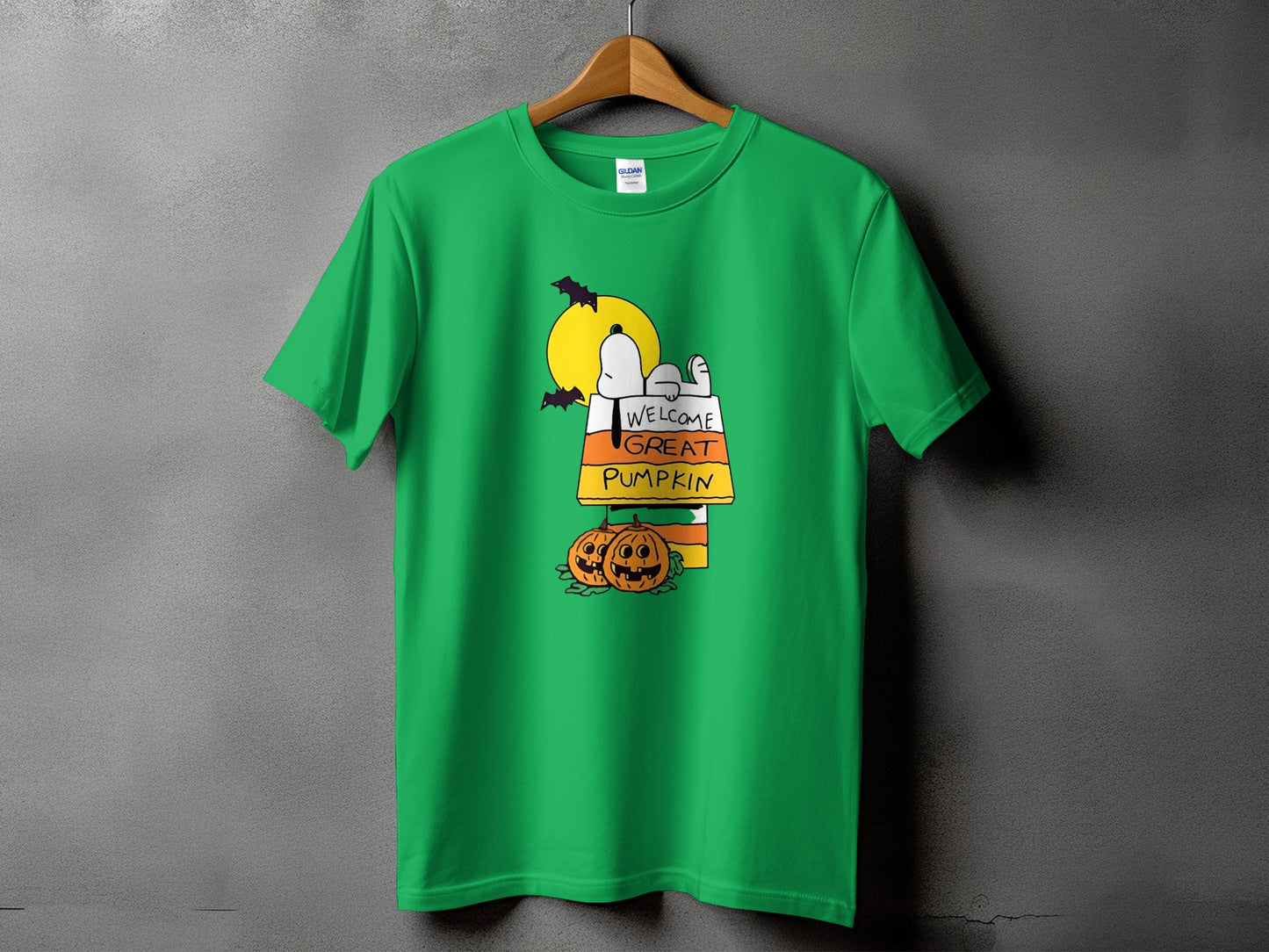 Green t-shirt with Snoopy, bats, moon, and pumpkins graphic saying "Welcome Great Pumpkin".