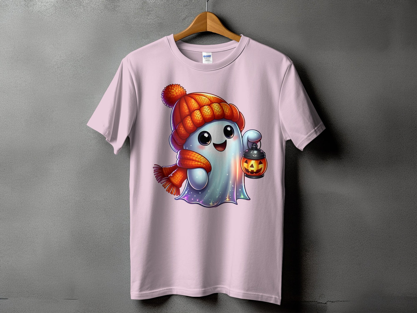 Pink t-shirt with cartoon ghost wearing hat and scarf holding jack-o'-lantern.