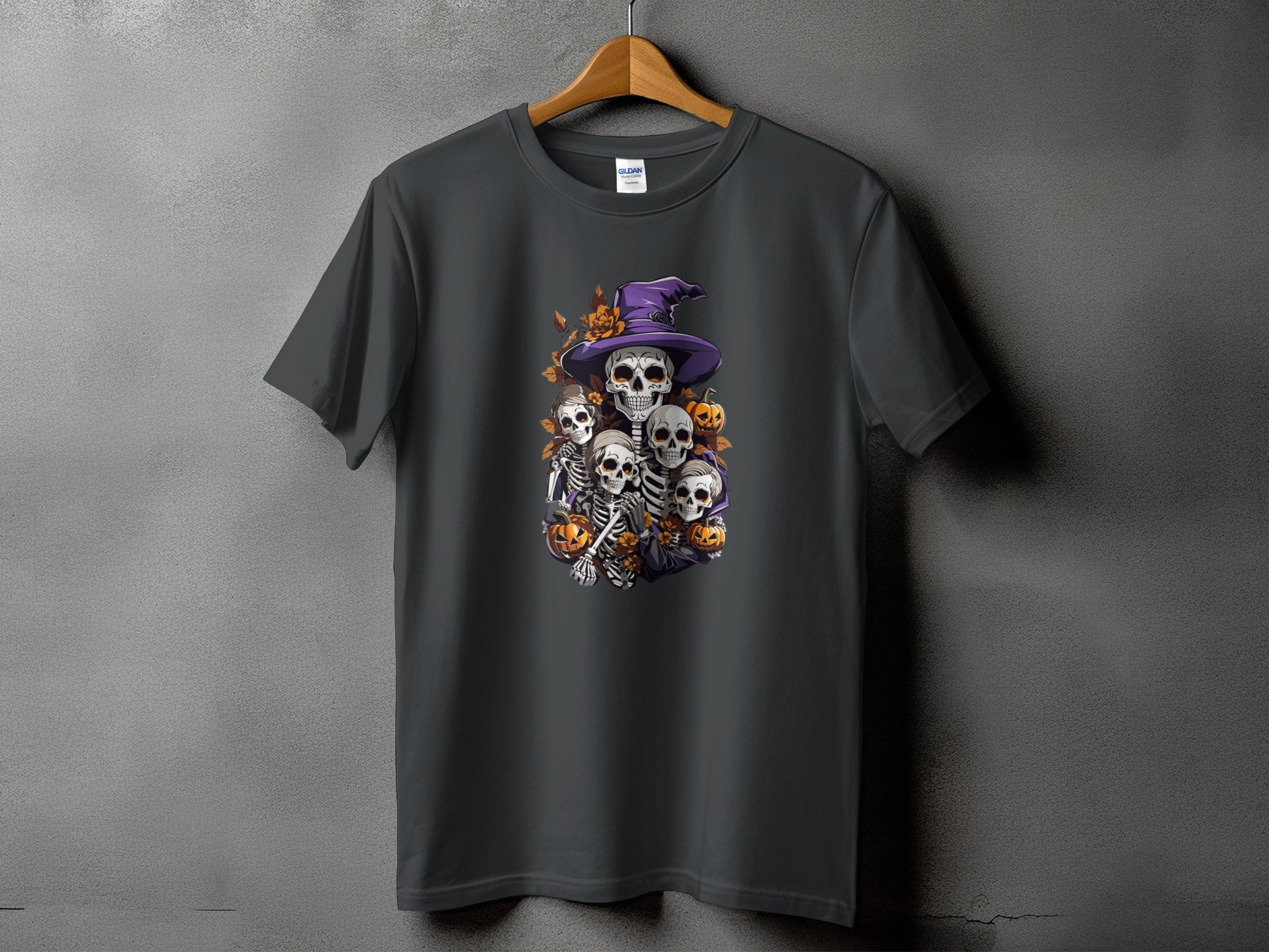 Dark grey t-shirt featuring a Halloween design of skeletons and pumpkins under a witch hat.