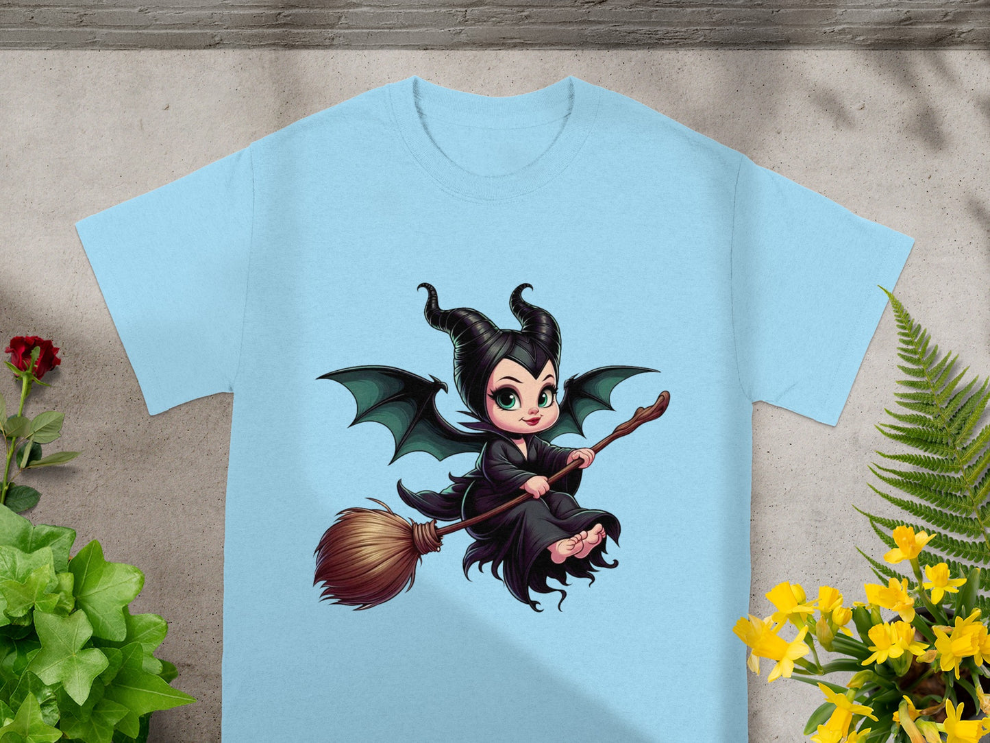 Baby Maleficent riding a broomstick on a light blue t-shirt.