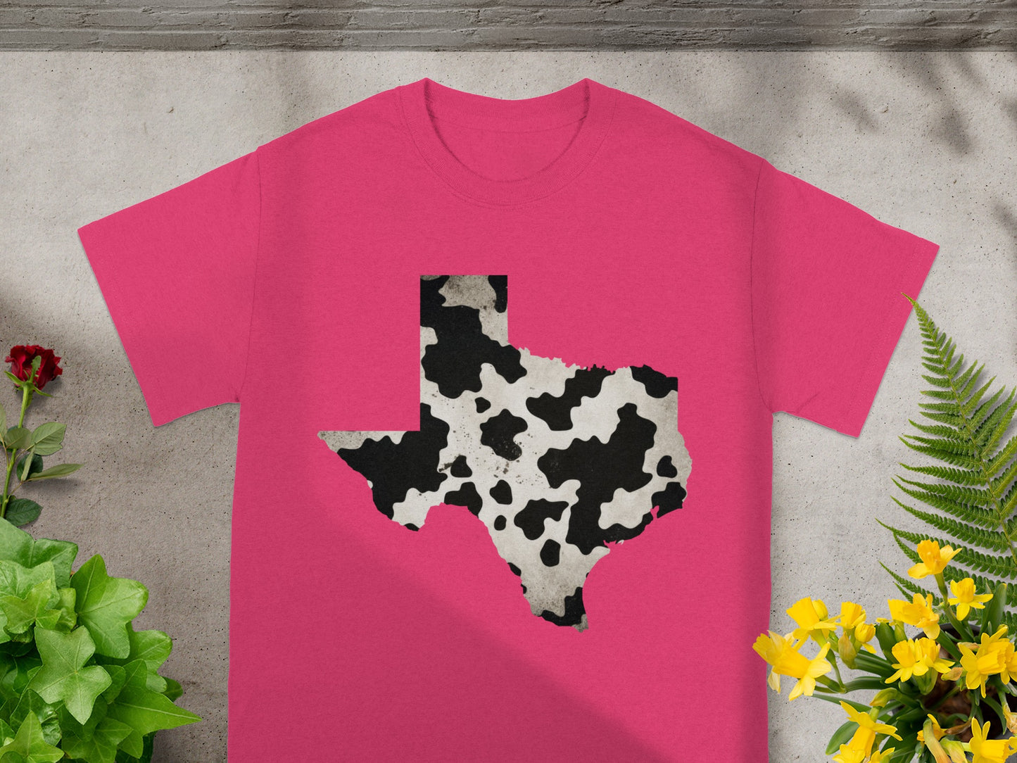Pink t-shirt featuring the state of Texas with a cow print pattern.