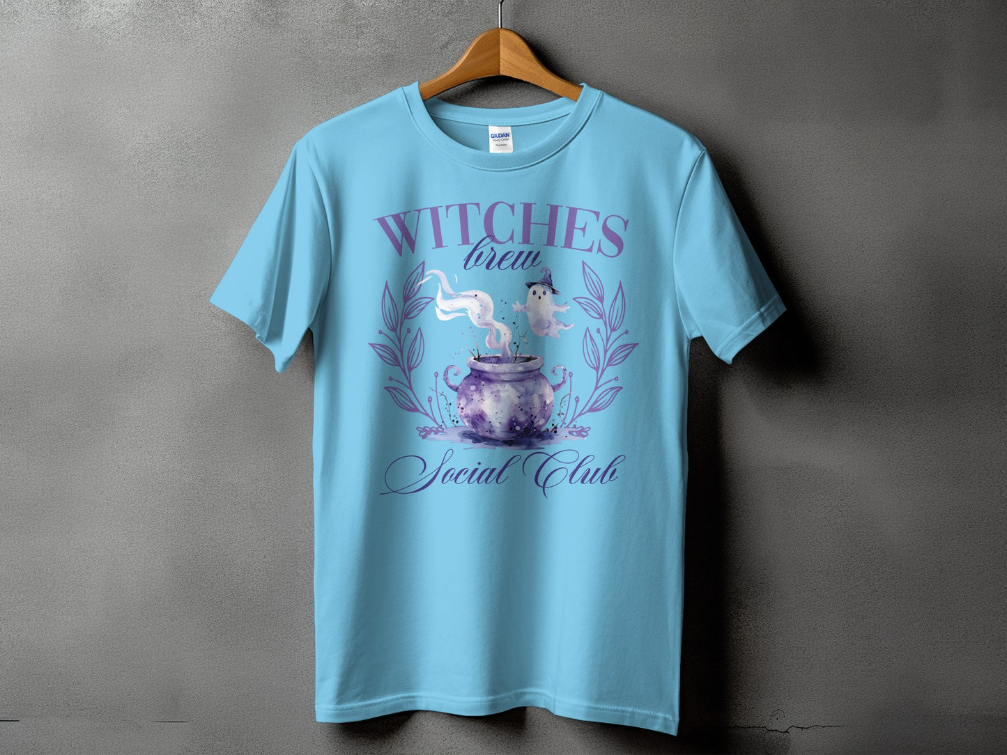 Light blue t-shirt with "Witches Brew Social Club" and watercolor cauldron graphic.