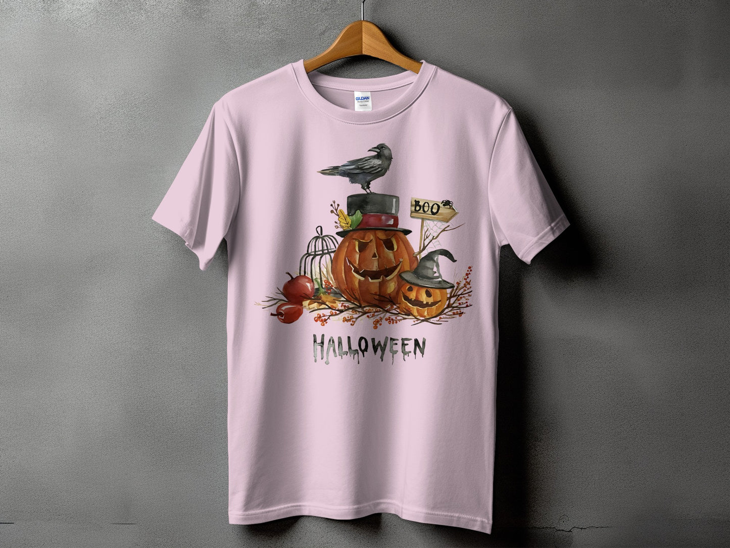 Pink t-shirt with watercolor Halloween graphic featuring pumpkins, a crow, and the word "Halloween".