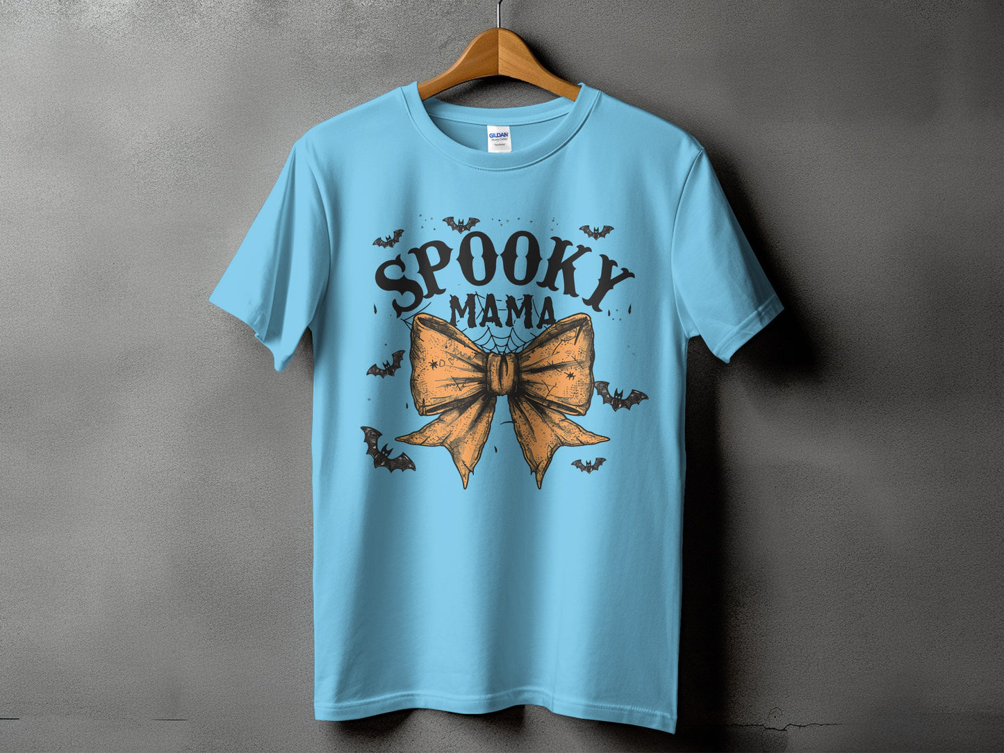 Light blue t-shirt with "Spooky Mama" text and orange bow graphic.