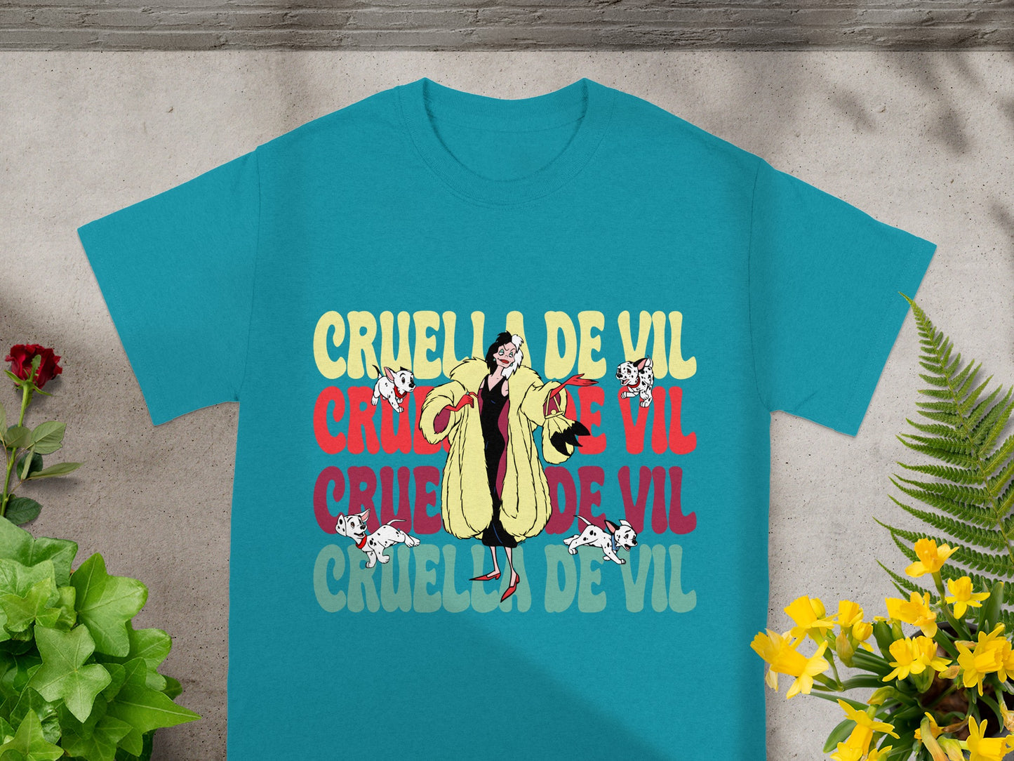 Teal t-shirt with "Cruella De Vil" repeated in colorful block letters.