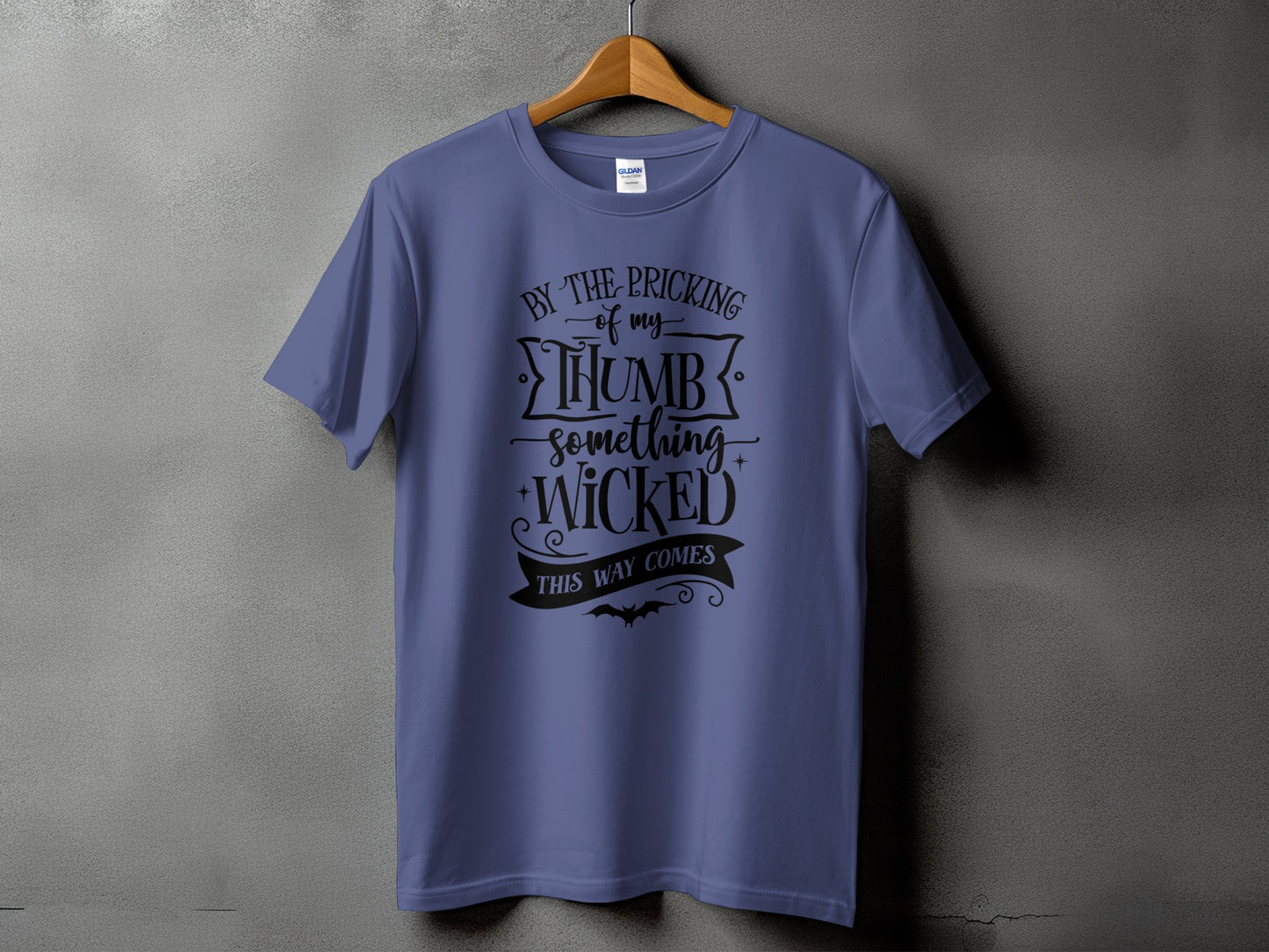 Purple t-shirt with black text "By the pricking of my thumb something wicked this way comes".