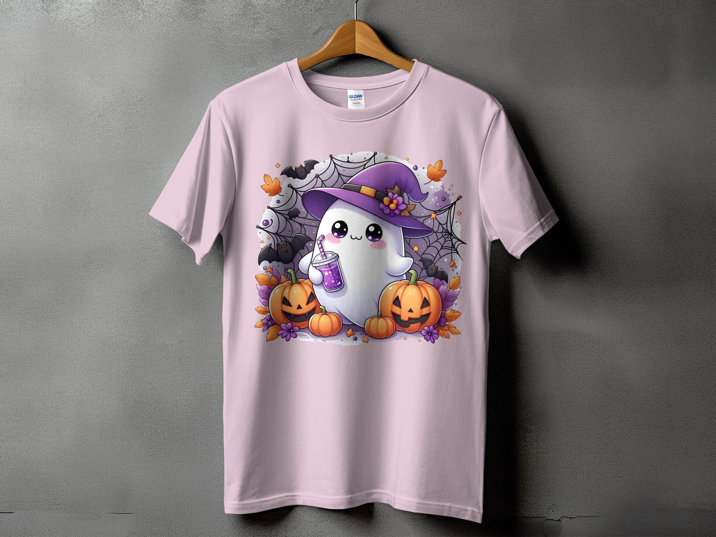 Pink t-shirt with a cute ghost wearing a witch hat and holding a drink, surrounded by pumpkins.