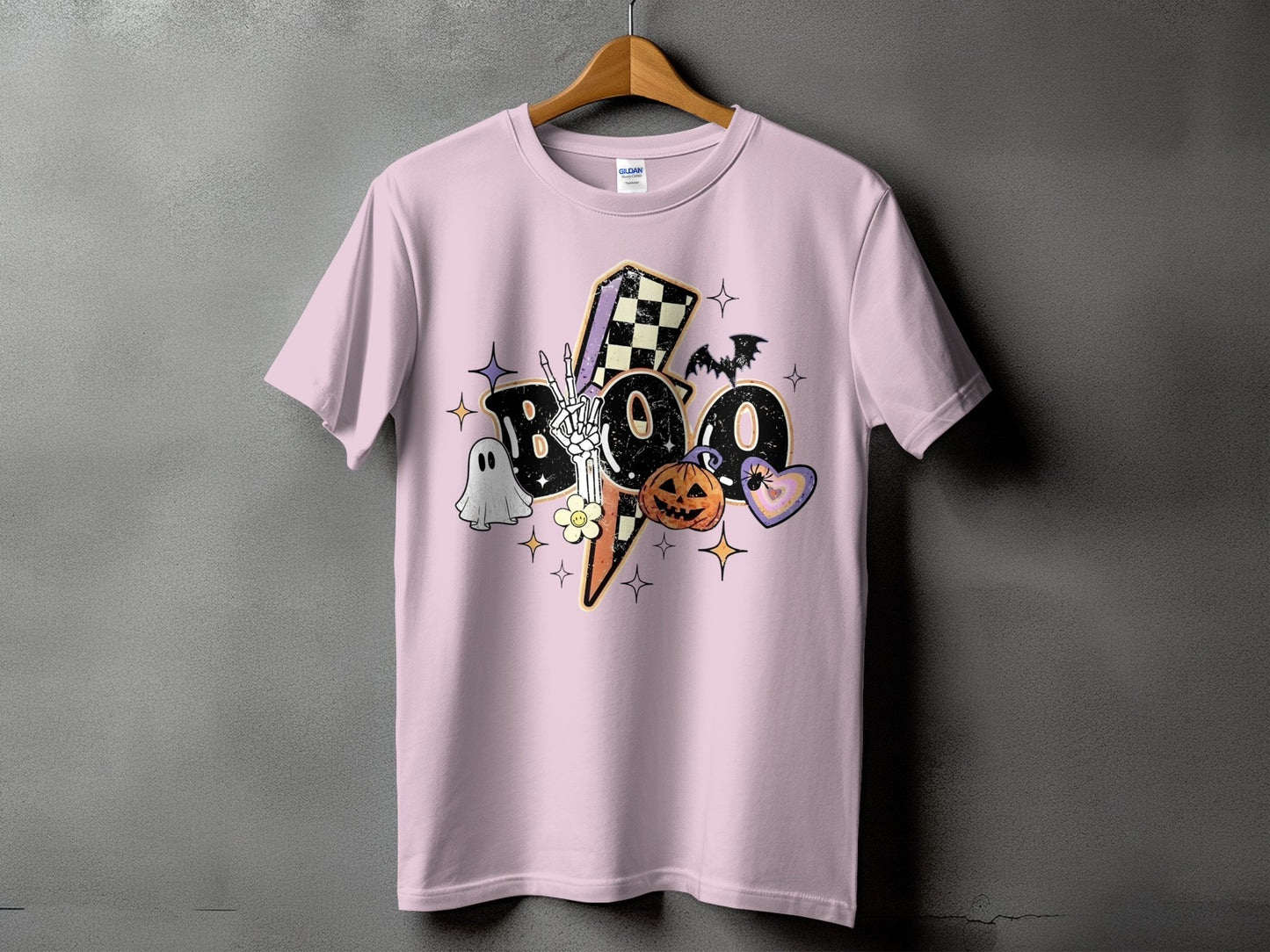 Pink t-shirt with "BOO" Halloween graphic featuring ghost, skeleton hand, pumpkin, and bat.